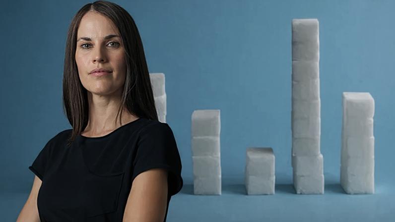A portrait of Melissa Hogenboom wearing a black top in front of an image of stacks of sugar cubes with a blue background (Credit: BBC/ Getty Images)