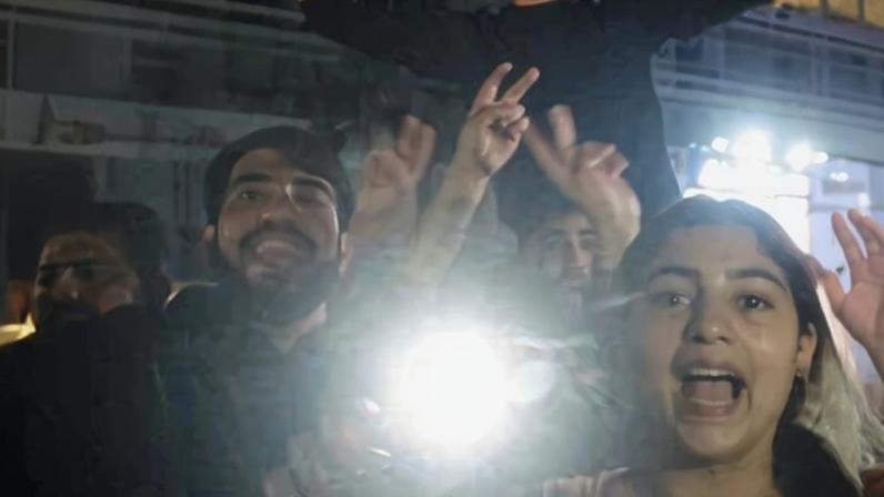 Group of people holding phones with flashlights on and celebrating
