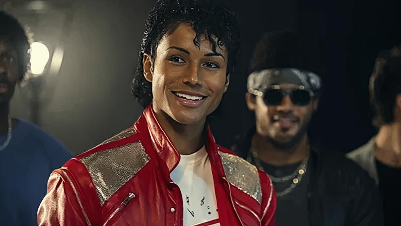 Universal A still of Jaafar Jackson wearing a red leather jacket and smiling at the camera in Michael biopic (Credit: Universal)