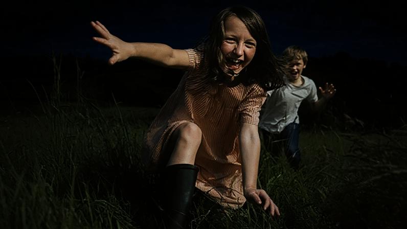 Getty Images A boy and a girl run joyously through a field (Credit: Getty Images)
