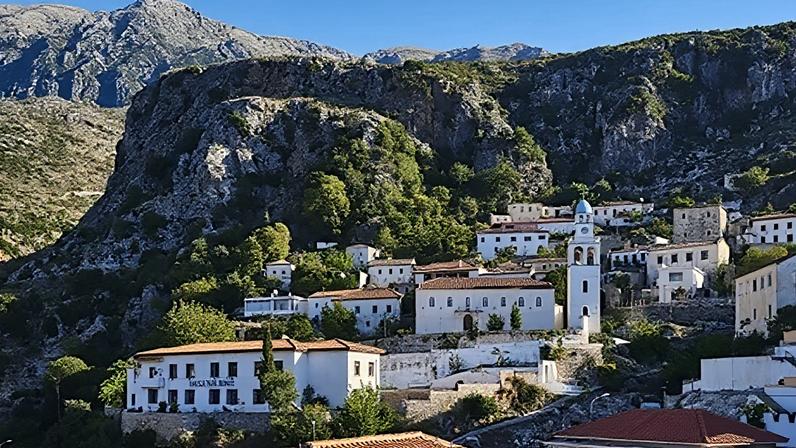 Getty Images Whitewashed buildings with terracotta roofs and a church bell tower on a mountainside on Albania's Adriatic Coast (Credit: Getty Images)