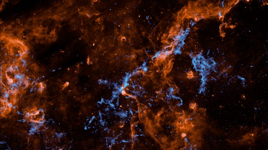Wispy filaments of vibrant orange and electric blue cosmic dust and gas weave through a dark, star-studded expanse of outer space, creating a chaotic and intricate web of celestial matter.