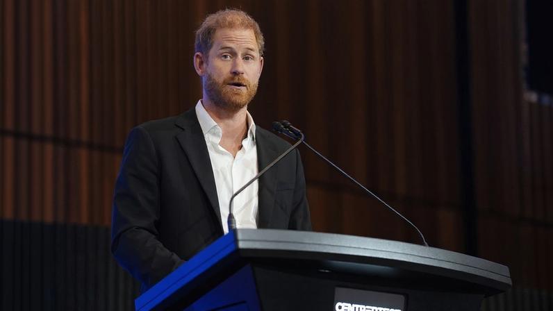 Foto colorida de homem de blazer preto falando em microfone - Metrópoles