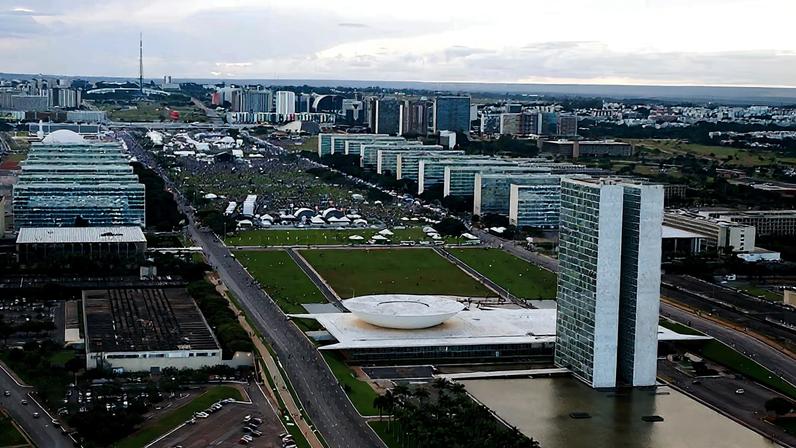 Vista aérea de Brasília ao entardecer, com o Eixo Monumental e o Congresso Nacional