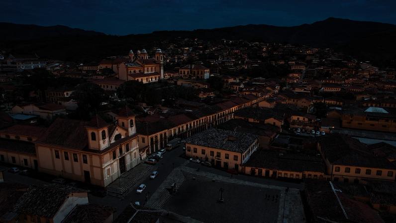 Vista urbana no interior de Minas Gerais, com prédios baixos e morros ao fundo