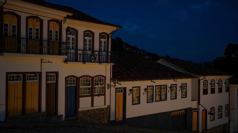 Centro histórico da Cidade de Goiás ao entardecer, com casario colonial e ponte de madeira sobre o Rio Vermelho