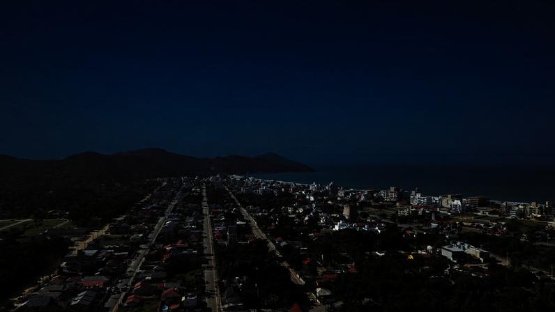 Vista aérea da Praia de Bombinhas SC, com mar azul e céu aberto.