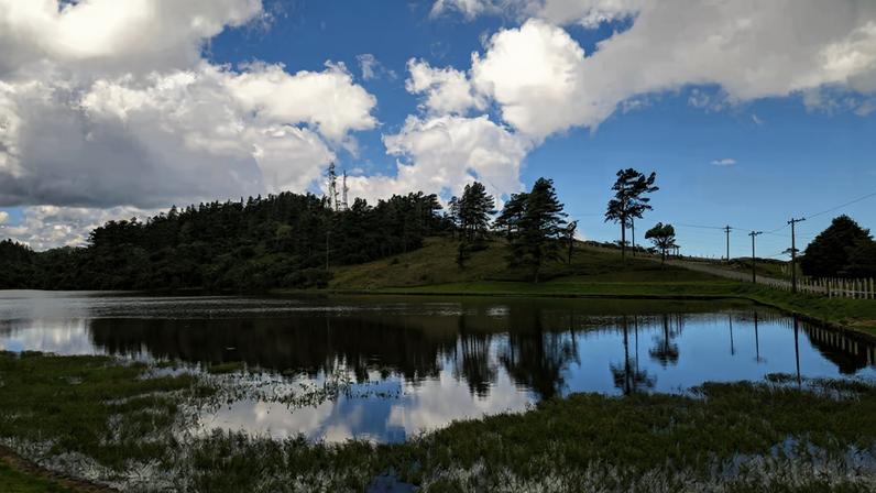 Paisagem da Serra da Mantiqueira ao entardecer, refletida em lago calmo. Créditos: Rio & Learn.