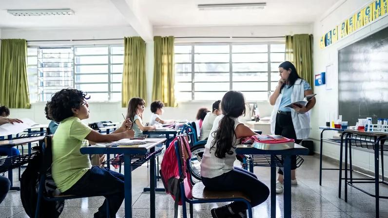 Sala de aula em escola pública do interior, com professora e alunos do fundamental em atividade, iluminação natural