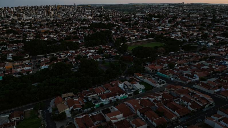 Vista aérea de Bauru, com prédios residenciais e áreas verdes ao entardecer.