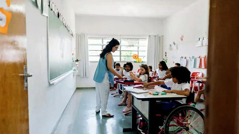 Sala de aula em escola pública, com professora e estudantes em atividade