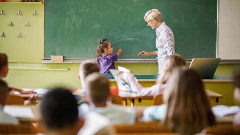 Sala de aula em escola pública, professora e alunos em atividade