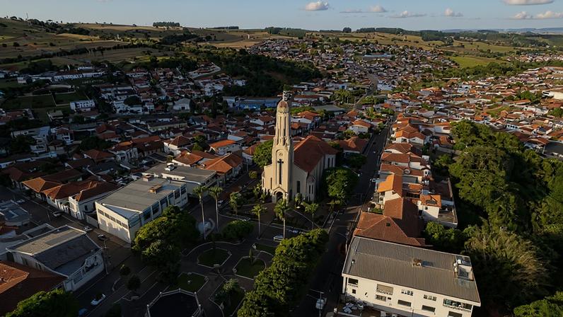 Vista aérea de uma cidade no Sul de Minas, com morros verdes ao fundo e área urbana ao centro
