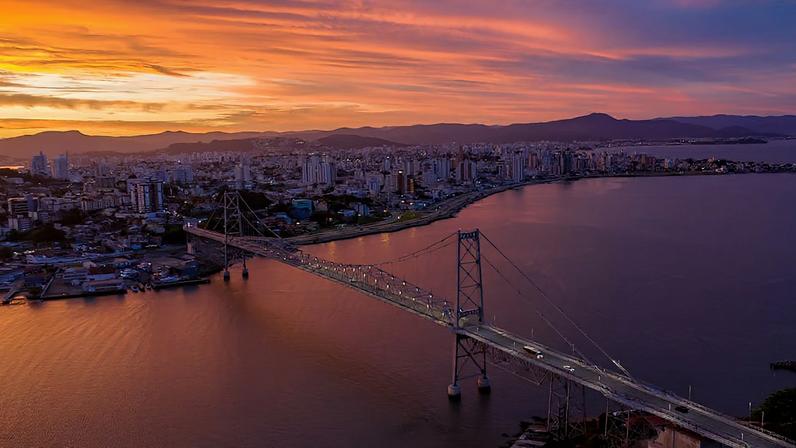 Florianópolis SC ao pôr do sol, com a Ponte Hercílio Luz em destaque. Créditos: Pexels.