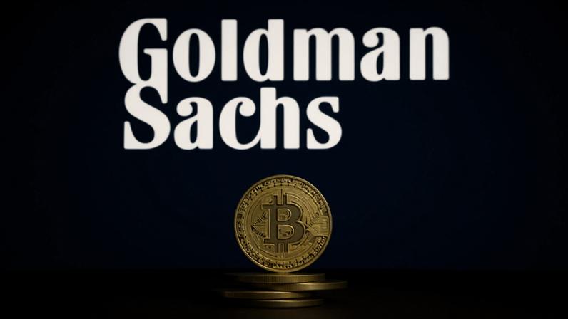 moeda de Bitcoin à frente do logotipo do Goldman Sachs