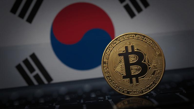 moeda de bitcoin à frente de tela que mostra bandeira da Coreia do Sul