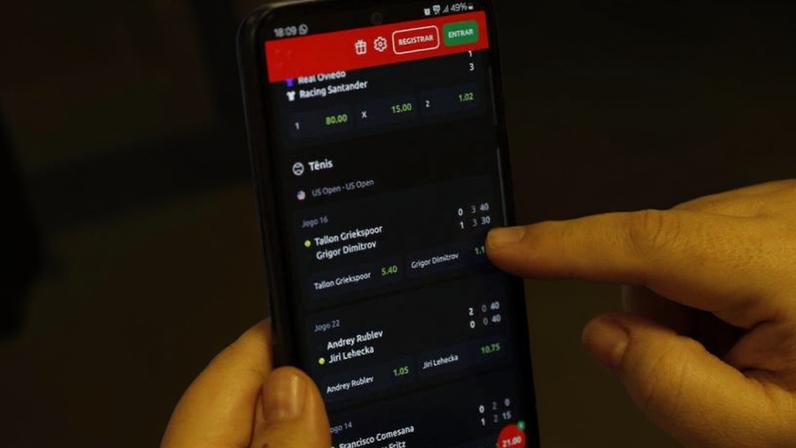 Um homem com um site de apostas aberto na tela do celular; a CNC disse que a bets impactaram o aumendo da inadimplência dos consumidores de mais baixa renda