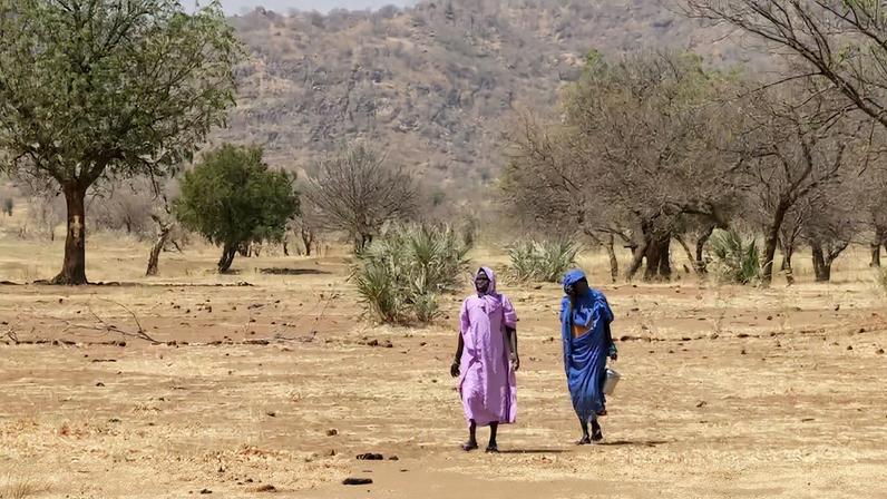 Pessoas caminham por uma área seca nas Montanhas Nuba, no Sudão, região afetada pela guerra e pelo deslocamento forçado