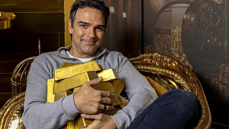 Tadeu Schmidt segura barras de ouro cenográfica em alusão ao prêmio recorde do BBB 26 que vai conhecer o ganhador na terça-feira (21), no feriado de Tiradentes