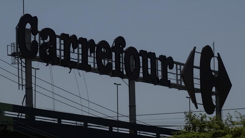 Trabalhadores fazem manutenção no logotipo de um supermercado Carrefour no Rio de Janeiro