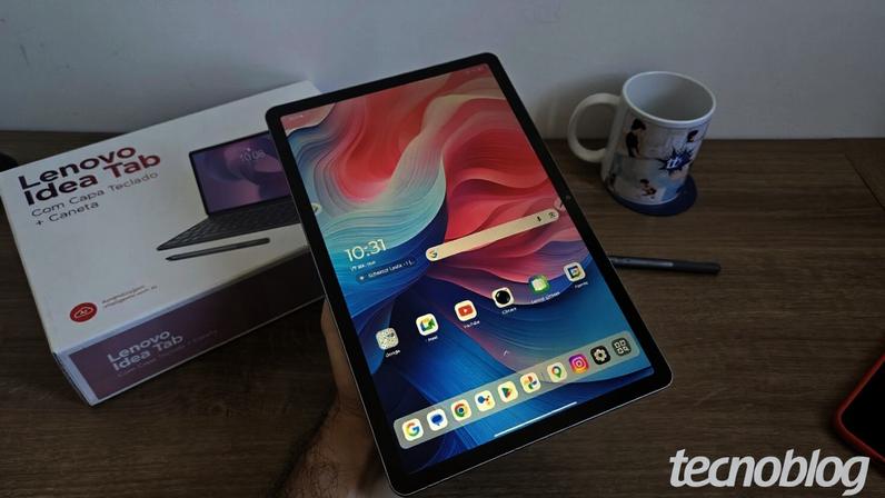 Tela de início do Lenovo Idea Tab; cenário composto pela caixa do produto, caneta do tablet e uma caneca do Tecnoblog.
