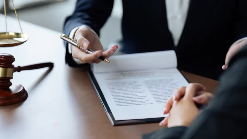 Duas pessoas em uma reunião profissional com documentos e símbolos jurídicos ao fundo.