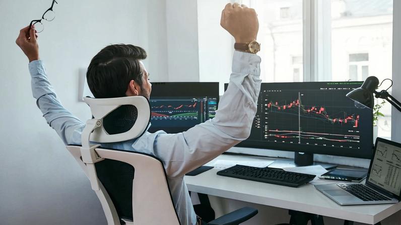 trader com braços levantados em frente a computador com graficos