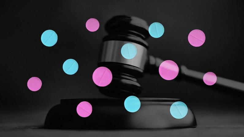 A gavel and pink and blue pills.