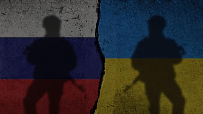 Imagem colorida de sombras de dois soldados em frente de parede pintada nas cores das bandeiras de Rússia (esquerda) e Ucrânia (direita) - Metrópoles