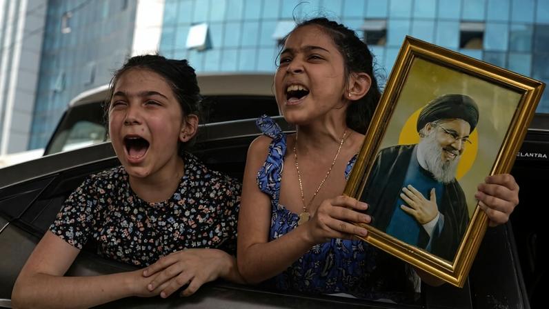 Two girls chant slogans as one holds an image of the late Hezbollah leader Hassan Nasrallah in Dahiyeh, Beirut's southern suburbs, Lebanon, Friday, April 17, 2026, following a ceasefire between Israel and Hezbollah.