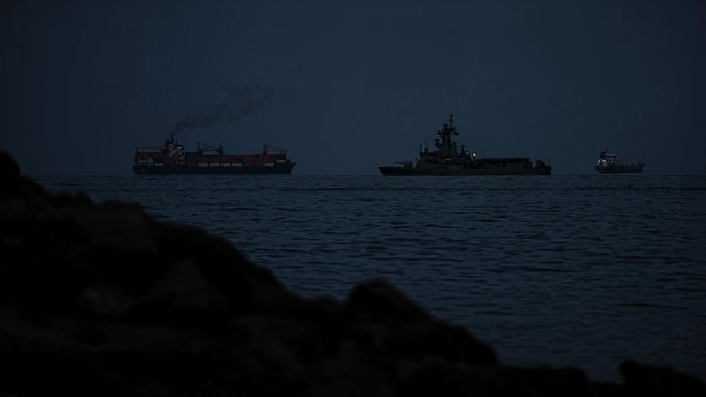 A UAE navy ship sails next to a cargo ship in the Strait of Hormuz as seen from Khor Fakkan, United Arab Emirates, Wednesday, March 11, 2026. (AP Photo/Altaf Qadri)