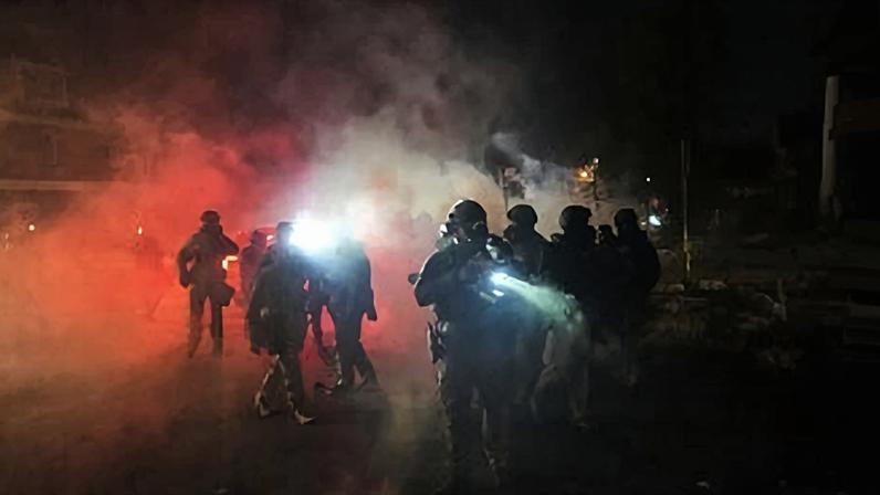 Law enforcement officers stand amid tear gas at the scene of a reported shooting, Jan. 14, 2026, in Minneapolis. (AP Photo/Adam Gray, File)