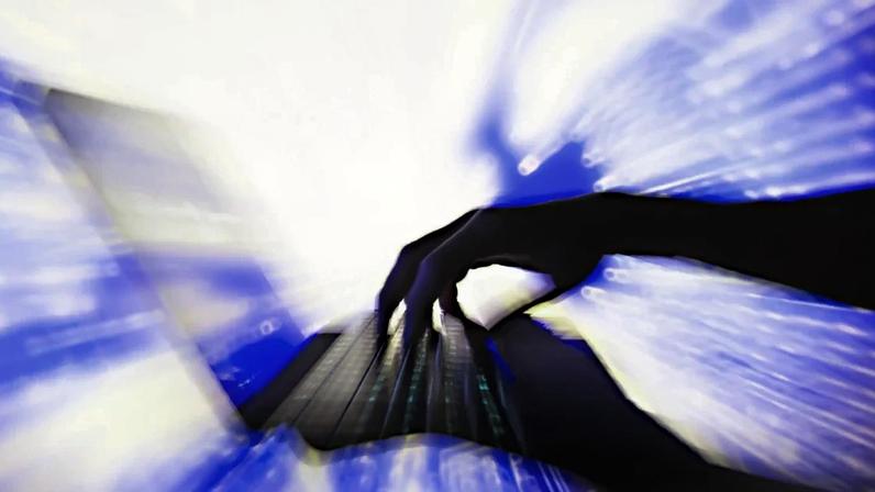 A imagem mostra uma mão em silhueta sobre um teclado de computador preto com iluminação sob as teclas. O fundo, desfocado em azul e branco, cria uma sensação de movimento e dinamismo, sugerindo rapidez na digitação ou interatividade digital, com padrões de luz evocando energia ou fluxo de dados.