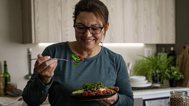 Foto colorida de mulher segurando garfo e prato com salada - Metrópoles