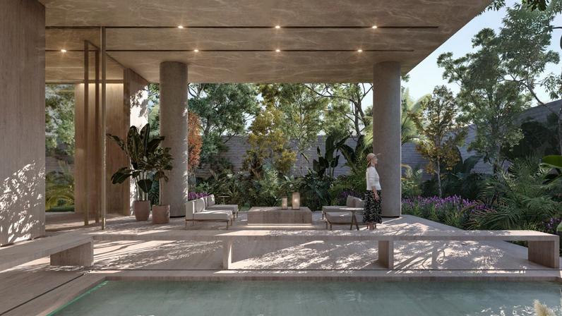 Área comum de edifício residencial com pé-direito alto, pilares de concreto e mobiliário contemporâneo. Uma mulher caminha pelo ambiente iluminado por luz natural.