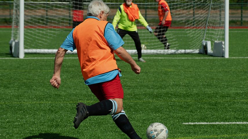 Fotografia de senhores de idade jogando futebol.
