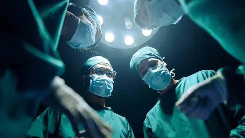 Foto de stock de ângulo baixo Quatro cirurgiões coordenando seus casos cirúrgicos Na sala de cirurgia, trabalho em equipe e cooperação