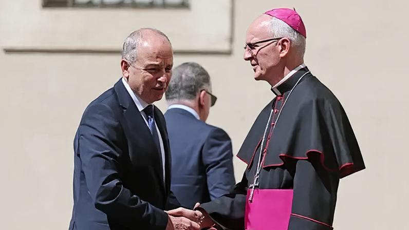 PA Media Taoiseach Michael Martin, wearing a navy suit, shaking hands with Prefect of the Papal Household Petar Rajic