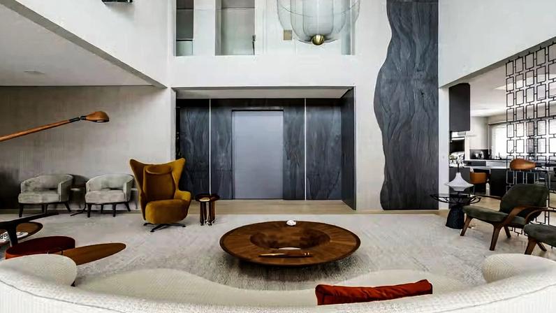 LIVING INTEGRADO | Com pé-direito alto e ambientes integrados, o living tem, logo na entrada, paredes revestidas de quartzito Wakanda Black levigado, da Alicante, com execução da Marmoraria Paulista. A poltrona mostarda Wing, de Jader Almeida, destaca-se pela cor, ao lado da mesa de apoio Bulle, assinada por Lucas Recchia. Tapete kilim da by Kamy