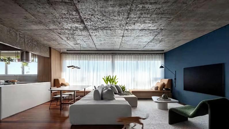LIVING INTEGRADO | Alguns elementos originais do apartamento dos anos 1970 foram preservados, como o piso de tabuão de madeira, além das vigas e a laje serem descascadas revelando o concreto para contar a história do imóvel. Sofá-ilha desenhado pelo escritório e executado por Reis Estofados. Poltrona verde Warp e mesa de centro Passeio, ambas da Mezas Design. Banco contínuo e funcional sob a janela feito de melamina amadeirada Itapuã, da Duratex, com floreira que abriga a planta estrelítzia