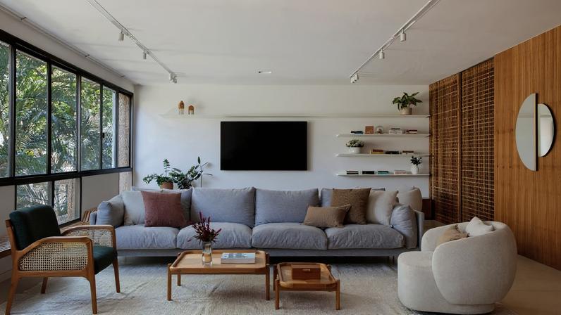 LIVING | Sofá Emma, da Breton, composto com poltronas Maya (branca), da Muui, e Arraia (verde), da Dü Design, na LZ Studio - mesmo autor e loja das mesas de centro Colombina. Almofadas da Galeria Hathi. Tapete Trama da Koord. O painel com portas em muxarabi, executado com MDF revestido com folha natural de freijó pela Marcenaria Bella Oliveira, permite integrar ou separar a brinquedoteca da sala de estar e TV. Espelhos Ensaio, da Ettérea, na Boobam. Iluminação da C.Lux. Vasos com plantas da Flor.Idas e arranjos florais criados por Camila Mesquita