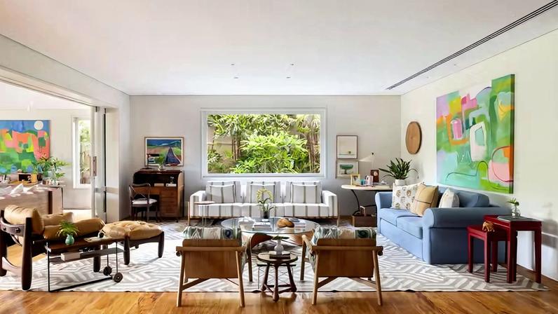 SALA DE ESTAR | Sob a janela, sofá Vittorio, de Isabelle De Mari, que também assina o par de poltronas Tokyo, na Olho Móveis, as quais foram revestidas com tecidos da Calê Home. Mesa de centro K2, assinada por Rafic Farah e Otávio Coelho. Poltrona Mole, de Sergio Rodrigues, na Dpot, mesmo autor do abajur Xibô, na Design Brasil. Escrivaninha antiga e obras de arte do acervo pessoal dos moradores. Tapete maior da Botteh. Piso de madeira peroba-rosa de demolição, da loja Efeito Madeira