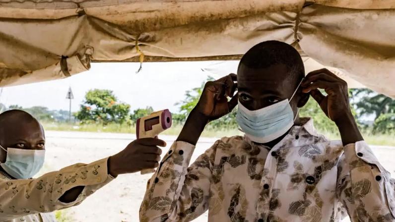 Um agente de saúde de fronteira no posto de travessia de Busunga, entre Uganda e a República Democrática do Congo, verifica a temperatura de um viajante usando um termômetro infravermelho sem contato em Bundibugyo, em 18 de maio de 2026.