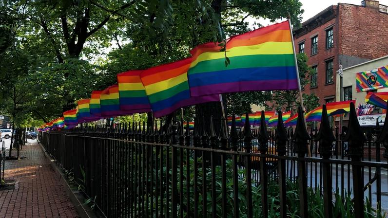 Pride flags along an iron gate.