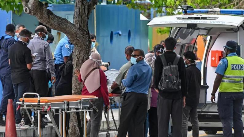 Equipes de emergência do Crescente Vermelho e policiais transferem os corpos de turistas italianos de uma lancha da polícia para uma ambulância em Malé, nas Maldivas, em 19 de maio de 2026.