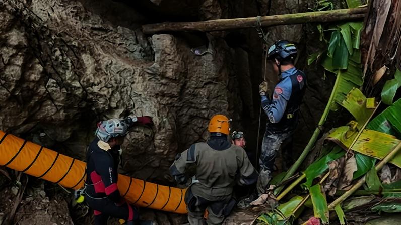 Members of a rescue team work to save the seven people trapped in a cave by flood waters.