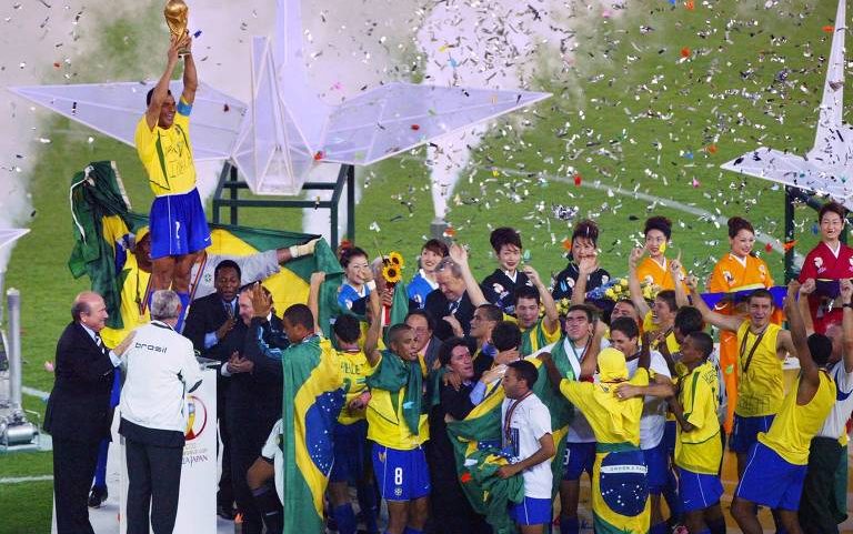 Brasil 2 a 0 Alemanha: o capitão da seleção brasileira, Cafu, ergue a taça observado pelos companheiros após a conquista do pentacampeonato, em Yokohama (Japão)