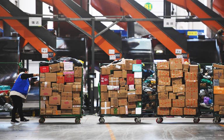 Empregados transportam pacotes em centro de logística em Zhengzhou, na província chinesa de Henan