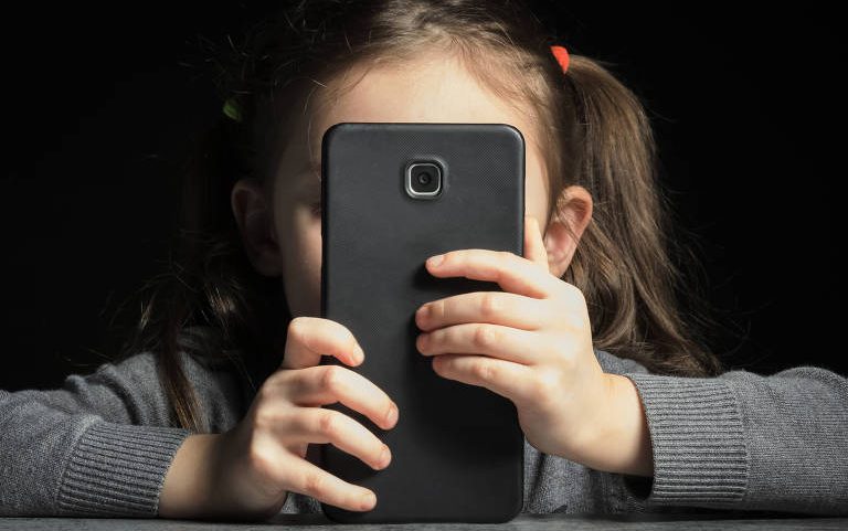 Menina atrás de um celular