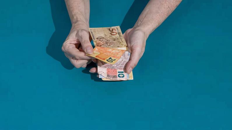 Pessoa manuseia cédulas de R$ 10, R$ 20 e R$ 50